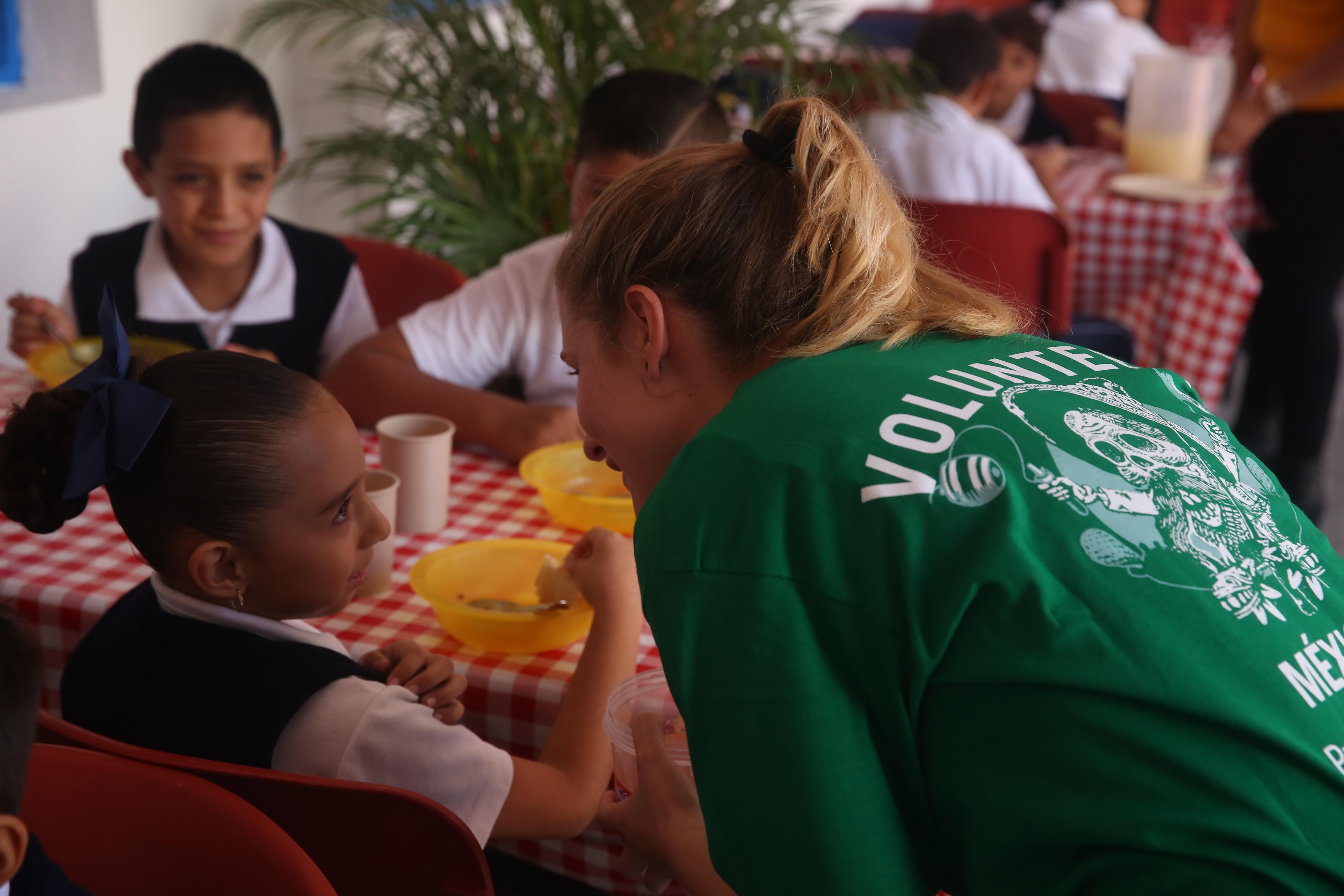 A volunteer working with children in Mexico engages children to practice speaking English during lunch at a care centre. Children practice their English with a Projects Abroad Childcare volunteer while having lunch at a care centre.